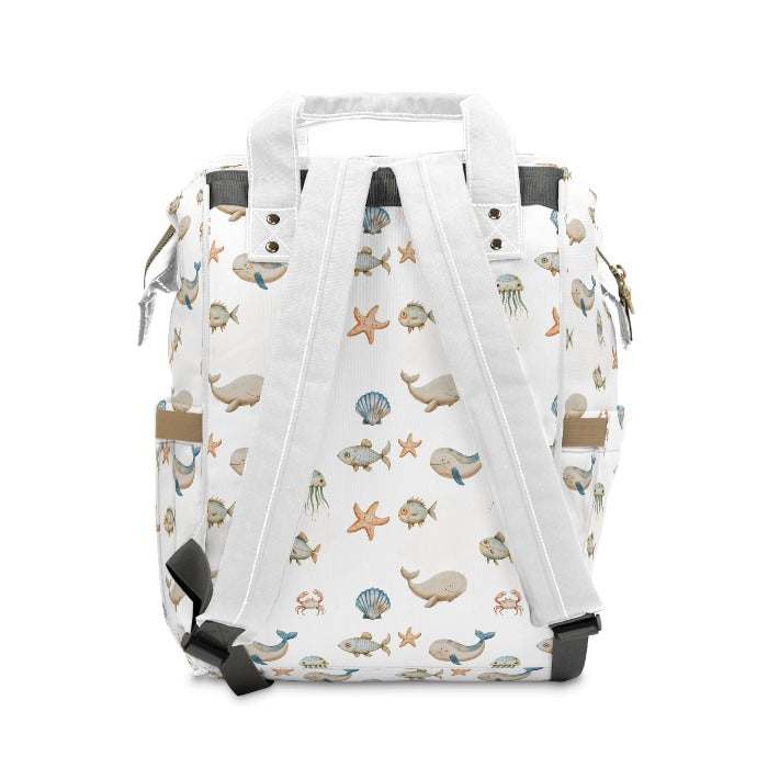 Ocean adventure-themed diaper backpack with a clean white backdrop, adorned with playful images of marine animals like whales, fish, crabs, starfish, and jellyfish, blending style with utility.