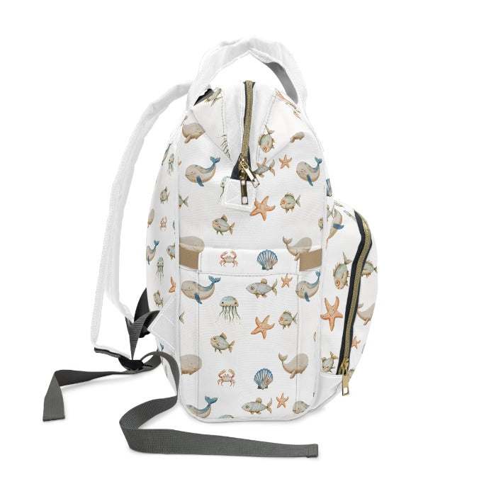 Eco-friendly diaper backpack with a minimalist white background, embellished with colorful oceanic life forms including whales, fish, crabs, starfish, and jellyfish, for environmentally conscious parents.