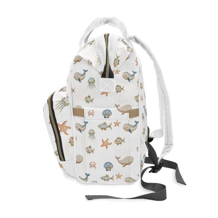 Lightweight and durable diaper backpack on a white background, decorated with a captivating ocean theme featuring whales, fish, crabs, starfish, and jellyfish, offering both charm and functionality.