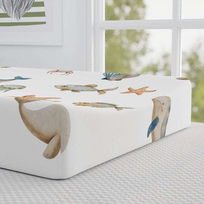 Hygienic and comfortable baby changing pad cover, set against a white backdrop and decorated with an engaging array of sea life including whales, fish, crabs, starfish, and jellyfish, designed for a soothing diaper change experience.