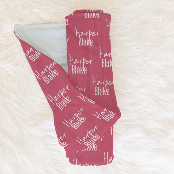 Rolled deep pink baby blanket featuring 'Harper Blake' script, ideal for stylish nursery bedding.