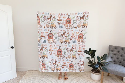 Customizable farm animal baby blanket, featuring a child's name integrated into the playful farm-themed design, perfect for nursery decor.